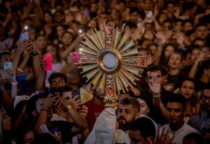 Ostensório erguido no meio da multidão durante a adoração no Luau com Cristo