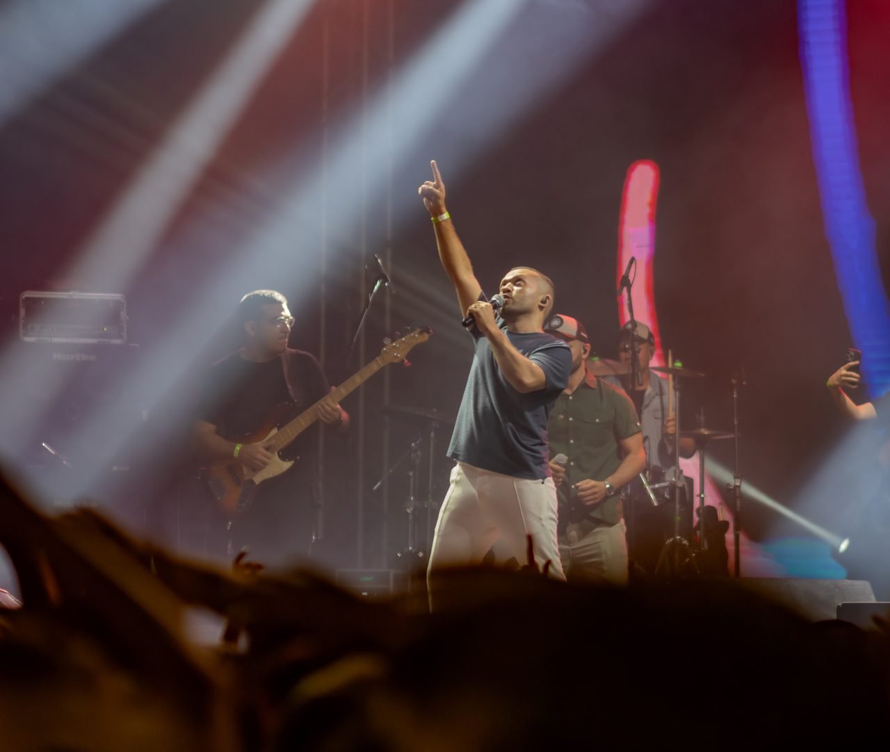 Vocalista apontando para o alto sob a luz do palco no Luau com Cristo