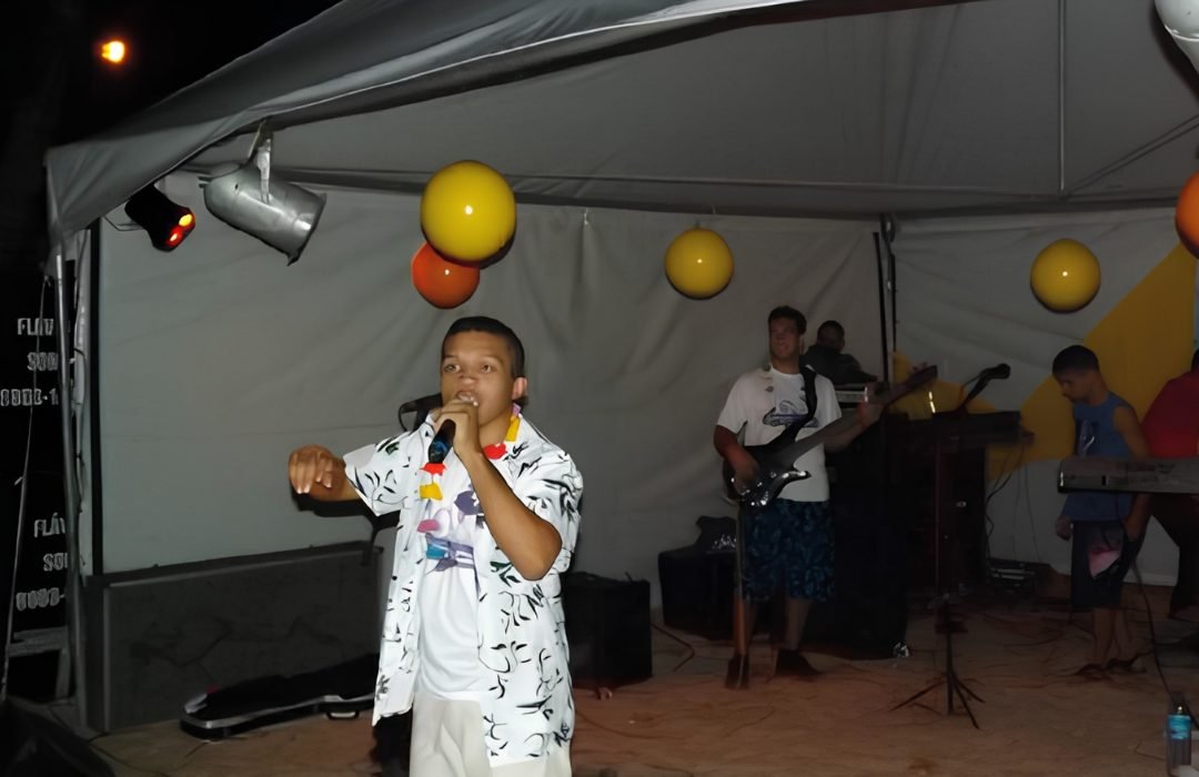 Vocalista cantando ao microfone sob a tenda do palco, com a banda ao fundo, numa das primeiras edições do Luau com Cristo
